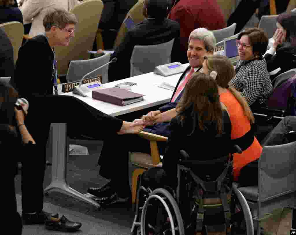 Theresia Degener, quien carece de brazos, miembro del comité de los derechos de las personas con discapacidades saluda con su pie al secretario de Estado John Kerry y a la embajadora de EE.UU. ante la ONU, Samantha Powers durante una reunión de alto nivel sobre discapacidad y desarrollo. 