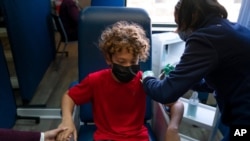 Max Cuevas, de 12 años, toma la mano de su madre mientras recibe la vacuna Pfizer COVID-19 en Tustin, California, el jueves 13 de mayo de 2021.