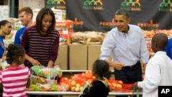 President Barack Obama, right, and first lady Michelle Obama participate in a Thanksgiving service project by handing out food at the Capital Area Food Bank in Washington, Nov. 27, 2013.