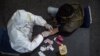 Seorang petugas kesehatan (kiri) mengambil sampel darah dari seorang pengendara motor yang melanggar Pembatasan Sosial Berskala Besar (PSBB) di sebuah kantor polisi di Surabaya, 3 Mei 2020. (Foto: AFP)