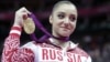Russian gymnast Aliya Mustafina displays the gold medal for her performance on the uneven bars during the artistic gymnastics women's apparatus finals at the 2012 Summer Olympics, Aug. 6, 2012, in London. 