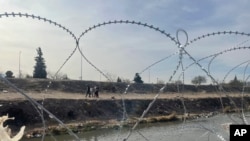 Una familia camina por el lado mexicano del Río Grande después de que las tropas de la Guardia Nacional de Texas cercaran el lugar en el sitio de los cruces masivos de migrantes en El Paso, Texas, el 20 de diciembre de 2022. 
