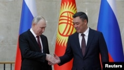 Presiden Rusia Vladimir Putin (kiri) menjabat tangan Presiden Kirgistan Sadyr Japarov dalam pertemuan di Bishkek, Kirgistan, pada 12 Oktober 2023. (Foto: Reuters/Vladimir Pirogov)
