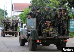 FILE - Government soldiers are seen atop military vehicles during their assault against rebels from the Maute group, who last year took over large parts of Marawi City, southern Philippines, June 13, 2017.