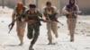 FILE - Kurdish fighters from the People's Protection Units (YPG) run across a street in Raqqa, Syria, July 3, 2017. 