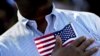 A candidate for citizenship holds the American flag at the start of a naturalization ceremony in Atlanta, Sept. 16, 2016. 