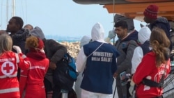 Un funcionario médico con un traje de protección debido al brote de coronavirus, verifica la temperatura de un migrante que desembarca del barco de rescate 'Open Arms' en Pozzallo, Italia, el 2 de febrero de 2020.