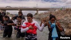 ARCHIVO - Yusniel, un migrante de Cuba, sostiene a su hijo de 10 días, Yireht, y a su esposa, Yanara, mientras buscan un punto de entrada más allá de una cerca de alambre a lo largo de la orilla del río Grande en Eagle Pass, Texas, EEUU, el 6 de octubre de 2023.