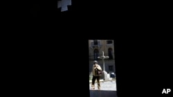 ARCHIVO-Una mujer, enmarcada por una puerta de la Iglesia Católica Merced, pasa en La Paz, Bolivia, el martes 2 de mayo de 2023. 