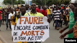 A man holds up a sign, reading "Faure still how many deaths by you," during an opposition protest against the rule of President Faure Gnassingbe in Lome, Togo, Sept. 6, 2017.
