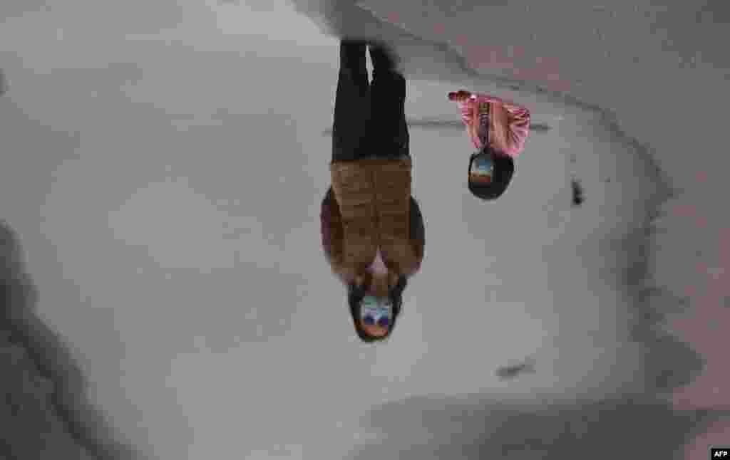 A mother and child wearing face masks are reflected in a puddle while walking in Melbourne&#39;s Docklands district in Australia as the city battles an outbreak of the COVID-19 coronavirus. 