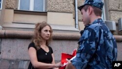 Maria Alekhina, a Russian activist of the feminist protest group Pussy Riot, talks to a policeman as she holds a protest against torture in front of the Federal Penitentiary in Moscow, Russia, Aug. 7, 2018. 