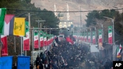 Una multitud de gente camina por una calle en dirección a la tumba del general Qassem Soleimani, general de la Guardia Revolucionaria de Irán, con una mezquita de fondo, en la ciudad de Kermán, a unos 820 kms (510 millas) al sureste de la capital, Teherán, el 4 de enero de 2024.