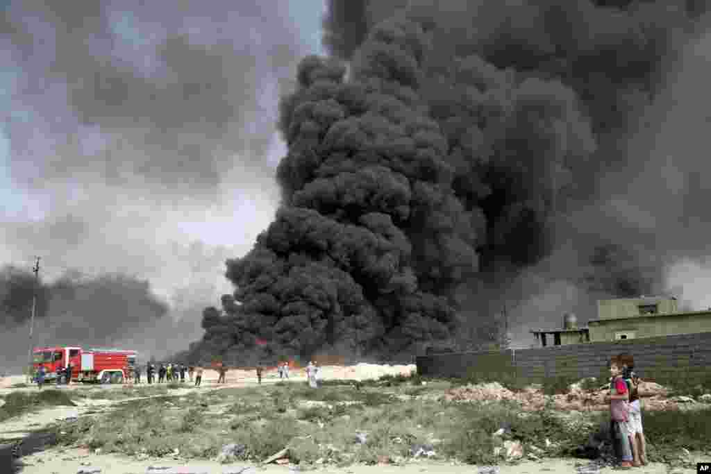 Pasukan Irak berusaha memadamkan sumur-sumur minyak yang dibakar ISIS di dekat kota Qayara, Irak.