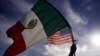 Un migrante ondea las banderas de México y Estados Unidos a su paso por el paso fronterizo del Chaparral, en Tijuana, México, el 22 de noviembre de 2018.