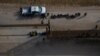 Menores no acompañados que buscan asilo se sientan en una fila cerca de un vehículo de la patrulla fronteriza de EE. UU. después de ser separados por agentes de unidades familiares en Penitas, Texas, EE. UU., el 17 de marzo de 2021.