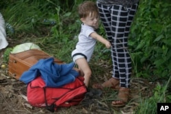 Un bebé se sostiene en la pierna de una mujer mientras viajan en una caravana de migrantes hondureños que se desplazan hacia Guatemala, en Ocotepeque, Honduras, el lunes 15 de octubre de 2018. La mujer y el pequeño forman parte de un grupo de migrantes hondureños que pretenden llegar caminando a Estados Unidos.