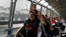 En esta foto del 29 de abril de 2019, migrantes cubanos son escoltados por agentes de inmigración mexicanos en Ciudad Juárez, México, al cruzar el puente internacional Paso del Norte para ser procesados como solicitantes de asilo.