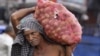 An Indian laborer carries a bag full of potatoes at a warehouse in Jammu, India, July 31,2012.