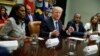 FILE - President Donald Trump, center, is flanked by White House staffer Omarosa Manigault Newman, left, and then-Housing and Urban Development Secretary-designate Ben Carson as he speaks during a meeting on African American History Month in the Roosevelt Room of the White House in Washington, Feb. 1, 2017. Manigault Newman released a new book "Unhinged," about her time in the White House.