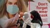 Perempuan mengenakan masker melewati poster promosi kesadaran pandemi Covid-19 di sebuah pusat perbelanjaan di Jakarta, 1 Juli 2020. (Foto: dok).