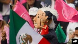 Manifestantes portan muñecos con la imagen del presidente Andrés Manuel López Obrador, y de la candidata presidencial Claudia Sheinbaum, en una marcha de organizaciones ciudadanas para exigir respeto por la autoridad electoral. El 19 de febrero en Ciudad de México.
