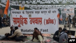 Protestors sits in front of a banner during a protest against last month's gang rape and murder of a student, in New Delhi, February 2, 2013.