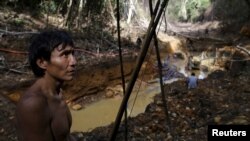 Indijanac Yanomami stoji u blizini ilegalnog rudnika zlata tokom operacije brazilske agencije za zaštitu životne sredine protiv ilegalnog vađenja zlata na domorodačkom zemljištu, u srcu amazonske prašume, u državi Roraima, Brazil, 17. aprila 2016.