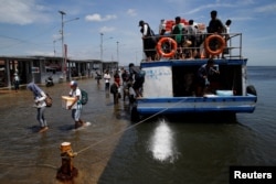 FILE - Passengers of a boat walk through rising sea water during high tide at Kali Adem port in Jakarta, Indonesia, Jan. 4, 2018.