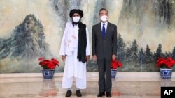 ARCHIVO - En esta foto del 28 de julio de 2021 publicada por la Agencia de Noticias Xinhua de China, el cofundador de los talibanes, Mullah Abdul Ghani Baradar, a la izquierda, y el ministro de Relaciones Exteriores de China, Wang Yi, posan para una foto en Tiajin, China.