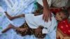 FILE - A father places his hand on his 7-year-old son, who is suffering from typhoid, in Pakistan's northwest Khyber Pakhtunkhwa province, Sept. 15, 2010.