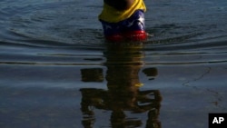 Un migrante con pantalones con un motivo de la bandera venezolana cruza el río Bravo desde Del Rio, Texas, para regresar a Ciudad Acuña, México, el 22 de septiembre de 2021.