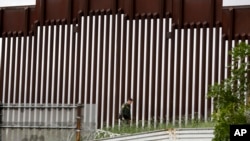 ARCHIVO - Un agente de la Patrulla Fronteriza de EEUU camina junto a una valla que separa a Tijuana, México, de San Diego, en San Diego, el 18 de marzo de 2020