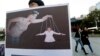 A South Korean college student holds a placard depicting South Korea's President Park Geun-hye, right bottom, as a marionette and Choi Soon-sil, who is at the center of a political scandal, as a puppeteer, in Seoul, South Korea, Nov. 3, 2016. 