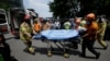Firefighters and rescue team members carry a injured man who set himself on fire during an anti-Japan rally demanding full compensation and an apology for wartime sex slaves from the Japanese government in front of the Japanese Embassy in Seoul, South Korea, Aug. 12, 2015.