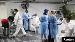 Viajeros se someten a pruebas para el COVID-19, mientras los países reaccionan a la nueva variante del coronavirus ómicron, fuera de la terminal internacional del aeropuerto de Sydney en Sydney, Australia, el 29 de noviembre de 2021.