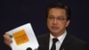 Malaysia's Transport Minister Liow Tiong Lai holds up a preliminary disaster report on the fate of Malaysia Airlines flight MH17 which crashed in eastern Ukraine, released by the Dutch Safety Board (DSB), during a press conference in Putrajaya, outside Ku