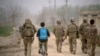 29 Mart 2012 - Afganistan'ın Kunduz vilayetinde sırtında Unicef çantasıyla bisikletine binen bir Afgan çocuk, bölgede görev yapan Alman askerlerinin arasından ilerliyor.