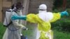 In this photo taken Sept. 9, 2018, a health worker sprays disinfectant on his colleague after working at an Ebola treatment center in Beni, Eastern Congo.