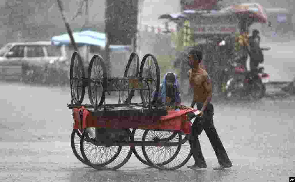 បុរស​ម្នាក់រុញ​រទេះ​មួយ​កណ្តាល​ភ្លៀង​ដ៏​ខ្លាំង​ក្នុង​ទីក្រុង Jammu ប្រទេស​ឥណ្ឌា។​