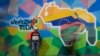 ARCHIVO - Un hombre vende cables para teléfonos frente a un mural de un mapa con el territorio del Esequibo incluido en Venezuela, en Caracas, el 11 de diciembre de 2023.