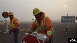 Mike Taylor y Kelly Busby, del estado de Arizona, instalan un punto de control en una carretera cerrada por los incendios en Picnic Hill.