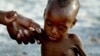 FILE - A mother holds onto her emaciated infant at an emergency feeding clinic in Maradi, Niger.