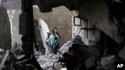 Niños palestinos caminan entre los escombros de un edificio derribado luego de un bombardeo israelí en Rafah, en la Franja de Gaza el jueves 14 de diciembre.