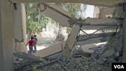 Dos niños pasan por la escuela donde autoridades libias dicen que hubo bombardeos por parte de la OTAN.