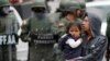 Un hombre que carga a una niña sale de un camino después de que soldados llegaran a reabrirlo en Quito, Ecuador, el lunes 7 de octubre de 2019. (AP Foto/Dolores Ochoa)