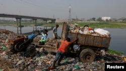 Trabajadores arrojan desechos junto al río Dhaleshwari, cuya agua fluye hacia el río Buriganga, en Savar, Bangladesh, el 7 de marzo de 2023. El Buriganga -o Viejo Ganges- está tan contaminado que su agua aparece completamente negra y emite un hedor fétido durante todo el año.