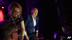 El senador Mark Kelly con su esposa, la exrepresentante Gabrielle Giffords, saludan a simpatizantes en Tucson, Arizona, el 8 de noviembre de 2022.