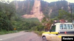 FILE - Locals inspect a landslide and damage to a road near the township of Tabubil after an earthquake that struck Papua New Guinea's Southern Highlands, Feb. 26, 2018.