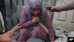 গাজা শহরে একজন ফিলিস্তিনি নারী মৃত স্বজনের হাত ধরে কাঁদছেন। ফাইল ফটোঃ ২৩ অক্টোবর, ২০২৩। 